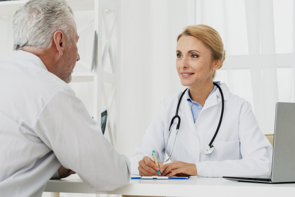 a female doctor talking to an older man who has pelvic floor pain.