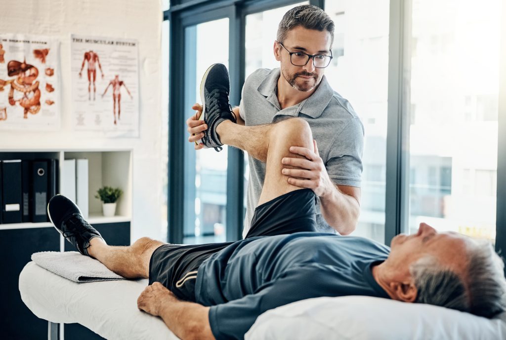 A male physiotherapist helping an older man do exercises to help his pelvic floor.