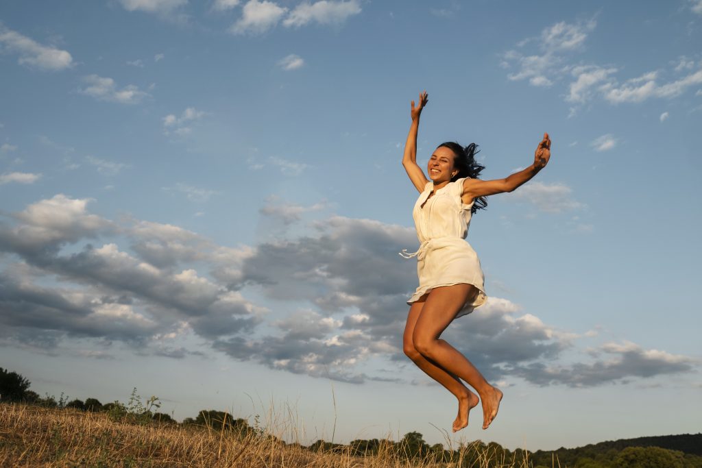 a woman jumping up in the air with a happy face from the freedom she feels from resolving her pelvic floor pain.